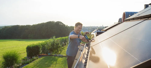Ein Mann bringt ein Solarmodul auf dem Dach an.