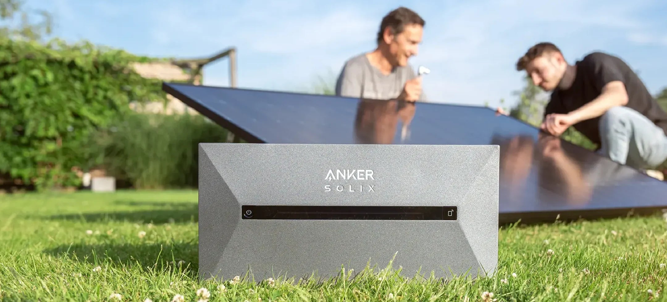 Anker SOLIX Speicher für ein Balkonkraftwerk. Im Hintergrund zwei Männer, die ein Solarmodul aufstellen.